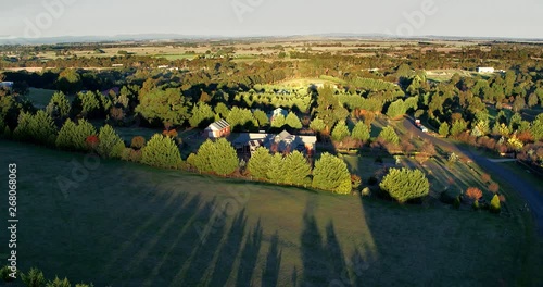 Part 2 of 2. Aerial flight above rural properties in a beautiful tree lined streets in late afternoon light with long shadows. File 2 of 2 - can be joined. photo