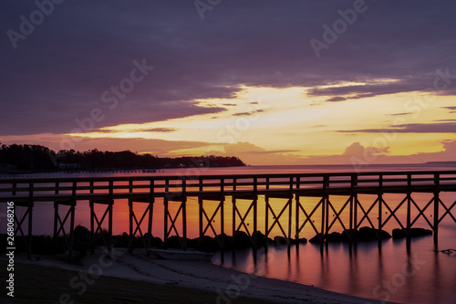 View from the shore of a long jetty in front of a beautiful sunrise at the Neuse River estuary at a park in Minnesott Beach  North Carolina.