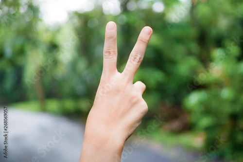 Hand with two fingers up in the peace or sign for symbol of peace or victory on natural background.
