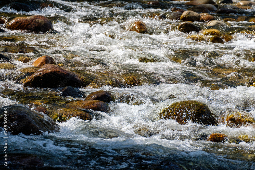fast water running down rocky creek inside park on a sunny day fast water running down rocky creek inside park on a sunny day