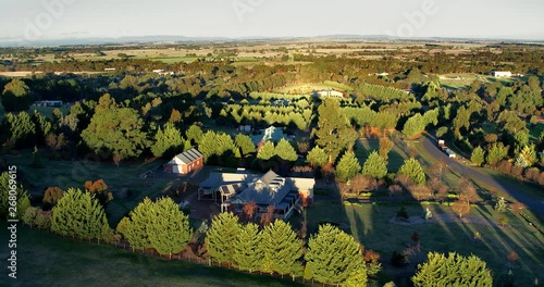 Part 1 of 2. Aerial flight above rural properties in a beautiful tree lined streets in late afternoon light with long shadows. File 1 of 2 - can be joined. photo
