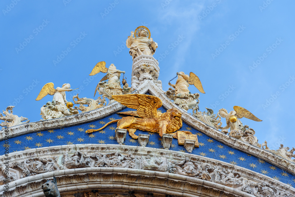 Detail of gable with Venice's patron apostle St. Mark with angels and underneath is winged lion on facade of Basilica of San Marco. Venice. Italy