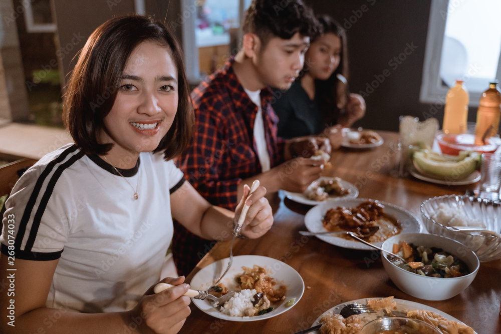 beautiful asian woman smiling to camera while having dinner at backyard garden party on summer day