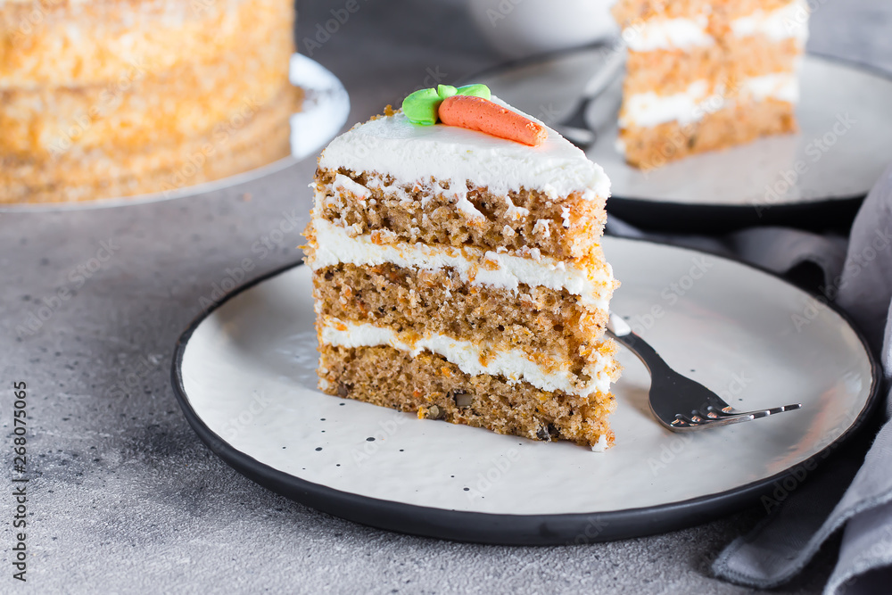 Slice of homemade carrot cake with cream cheese frosting on plate on gray stone table background Slice of homemade carrot cake with cream cheese frosting on plate on gray stone table background