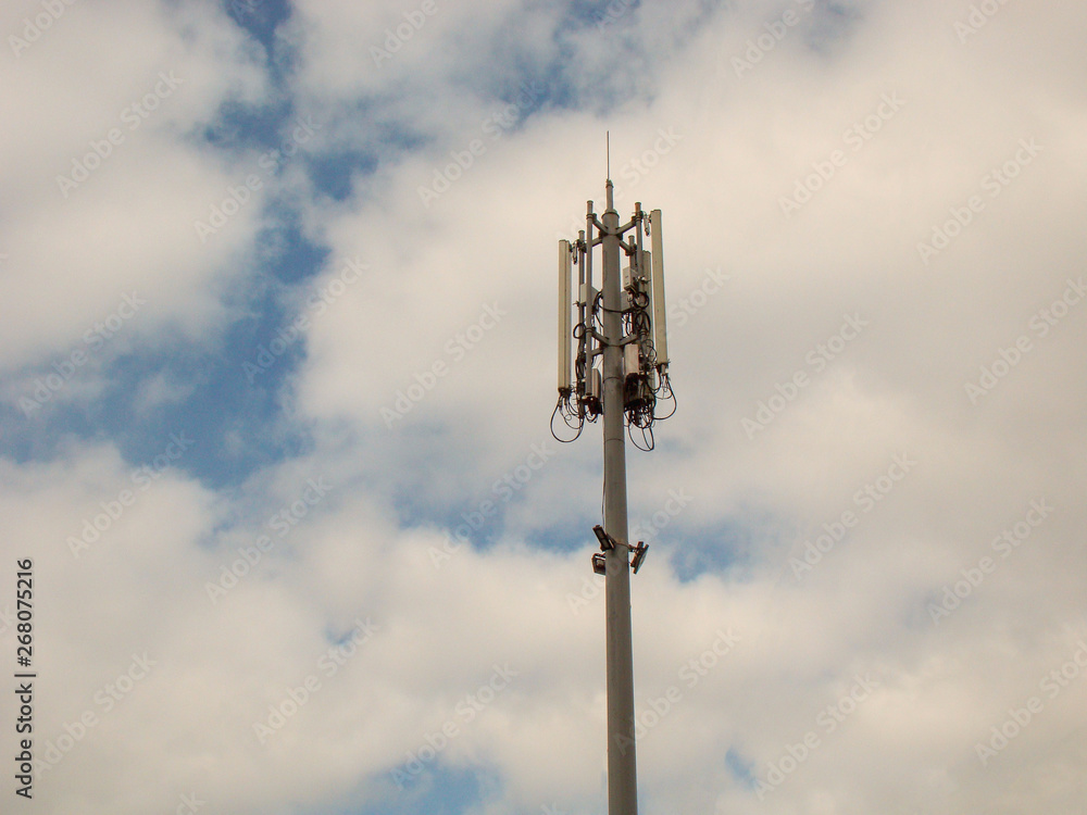 A cell site, tower, or cellular base station - enabled mobile device site where antennae and electronic communications equipment are placed. Concrete pillar, sky background. A cell site, tower, or cellular base station - enabled mobile device site where antennae and electronic communications equipment are placed. Concrete pillar, sky background.
