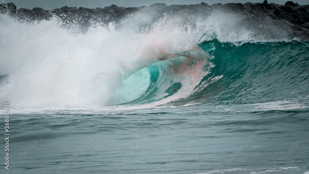 A large barreling wave crashing onto the shore spraying mist A large barreling wave crashing onto the shore spraying mist