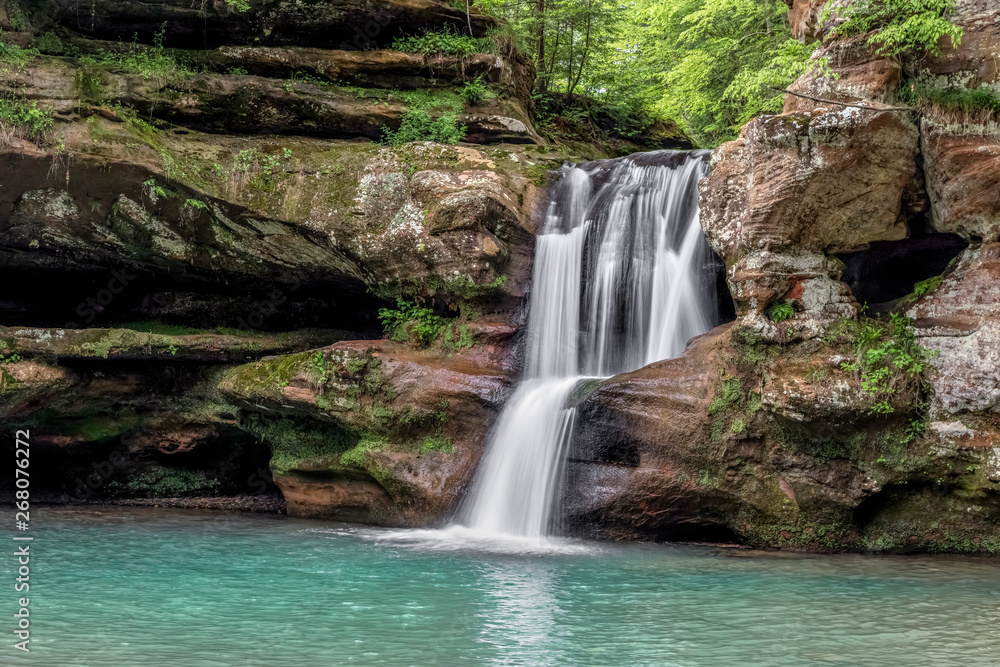 Sandstone Cascade in the Hocking Hills - Upper Falls at Old Man’s Cave is a beautiful waterfall that cascades over a sandstone cliff in Hocking Hills State Park, Ohio. Sandstone Cascade in the Hocking Hills - Upper Falls at Old Man’s Cave is a beautiful waterfall that cascades over a sandstone cliff in Hocking Hills State Park, Ohio.