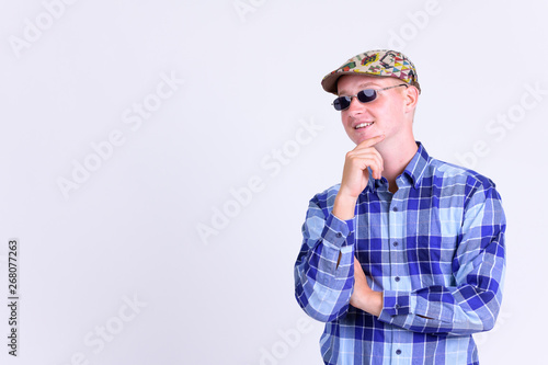Happy young hipster man with sunglasses thinking