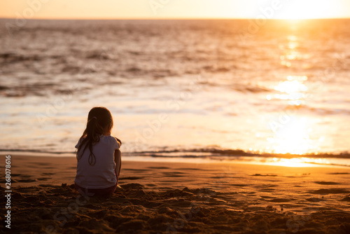 Isolated girl child facing towards sea during sundown