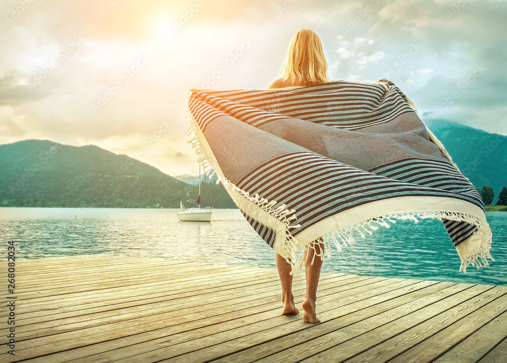 Obraz premium Happiness blonde woman stay on the wooden pier near the mountain