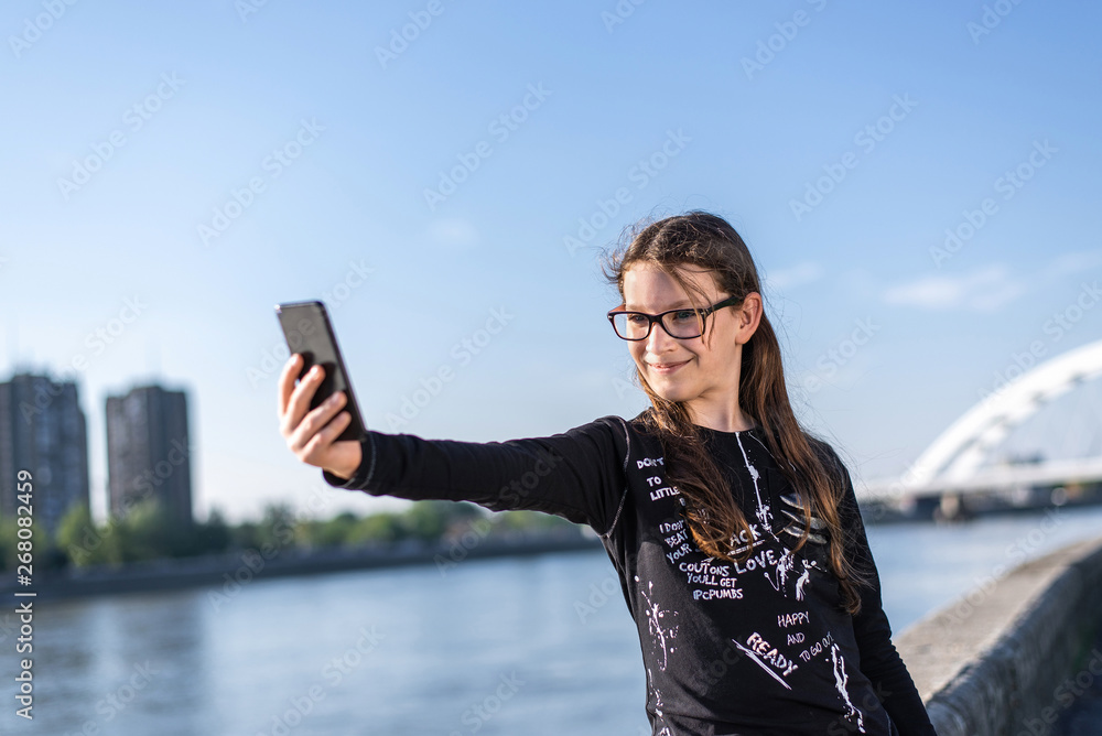 Young urban girl with glasses, pre-teenager, taking selfie photo