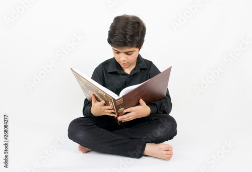 Muslim young boy reading Quran, the holy book of Islam photo