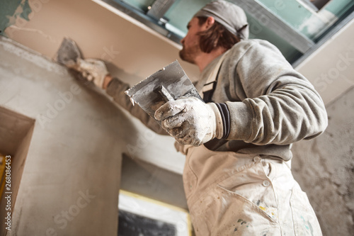 Workman plastering gypsum walls inside the house. photo