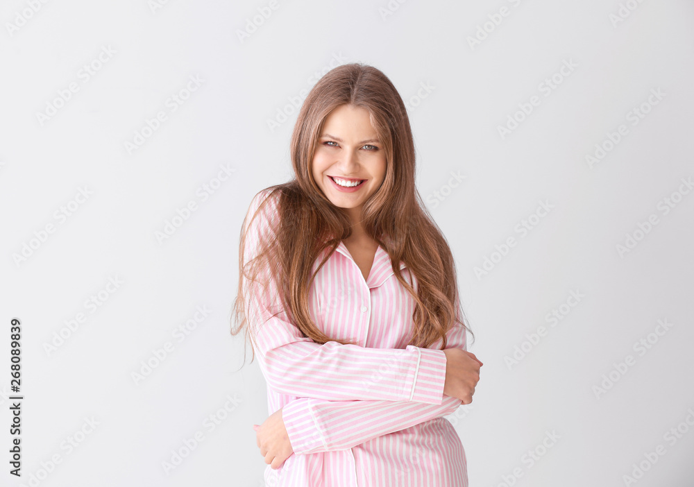 Beautiful young woman in pajamas on light background Beautiful young woman in pajamas on light background