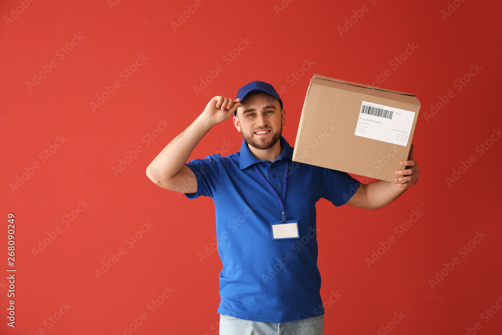 Handsome delivery man with box on color background Handsome delivery man with box on color background