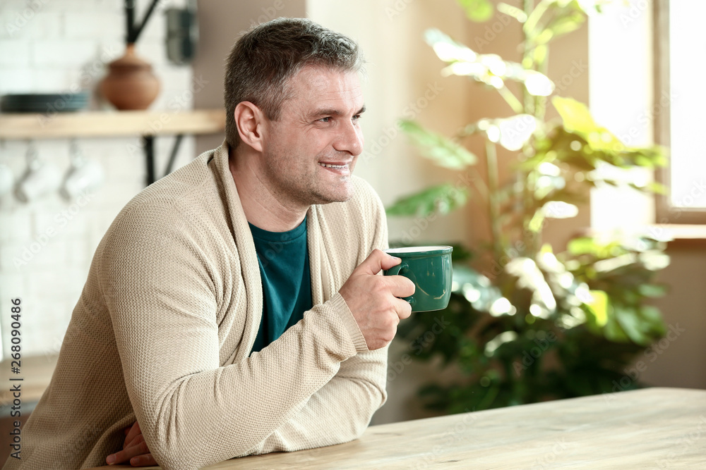 Handsome mature man drinking coffee in kitchen at home Handsome mature man drinking coffee in kitchen at home