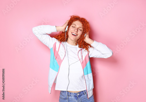 Beautiful redhead woman listening to music on color background © Pixel-Shot