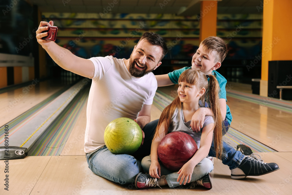 Fototapeta premium Man and his children taking selfie in bowling club