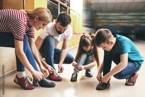 Family changing shoes before playing bowling in club