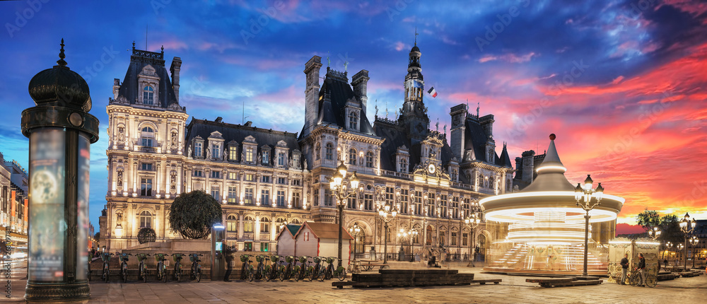Paris City Hall (Hotel de Ville) at sunset with spinning carousel in the front square. Paris, France.