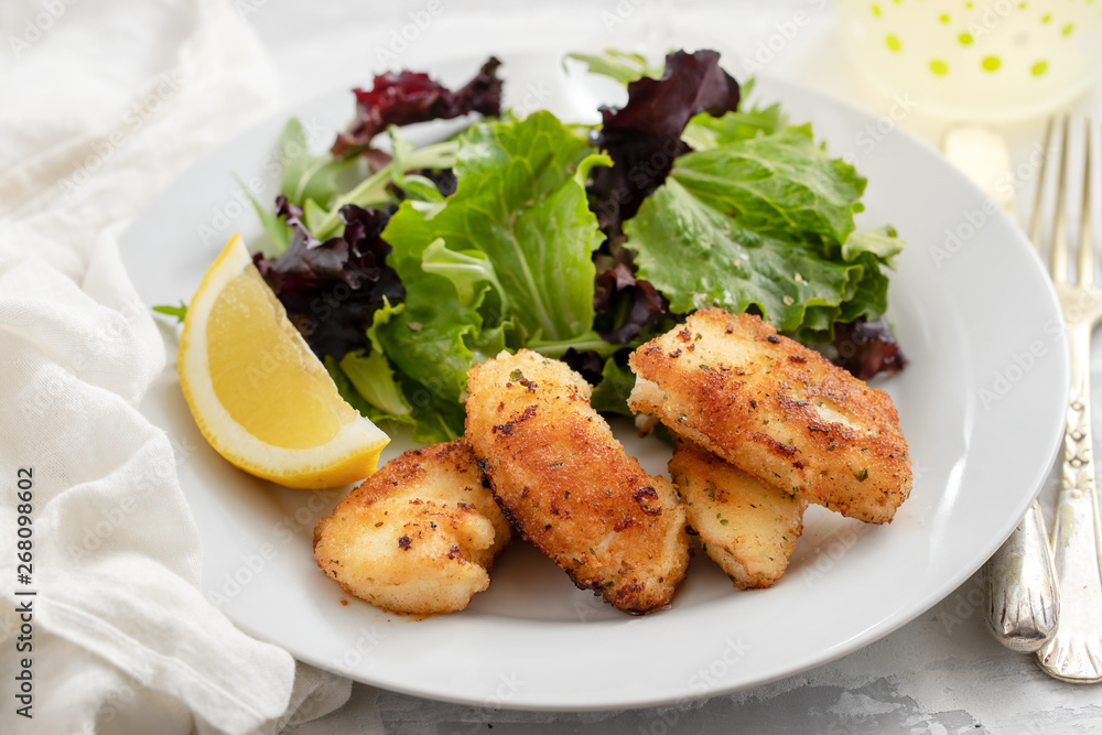fried squid with salad and lemon on white plate fried squid with salad and lemon on white plate