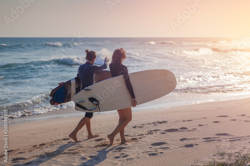 Photography Young beautiful loving couple friends on the sand by the ocean with surfboards a