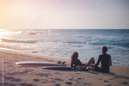 Photography Young beautiful loving couple friends on the sand by the ocean with surfboards a