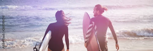 Obraz Młoda piękna para przyjaciół nad oceanem z deskami surfingowymi w rękach, panoramiczny nagłówek banera