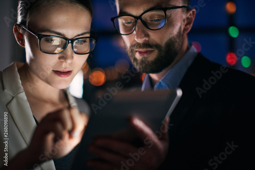 Two business people working on tablet at night photo