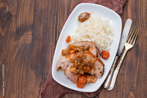 baked turkey leg with vegetables, smoked sausage, herbs and boiled rice on white dish