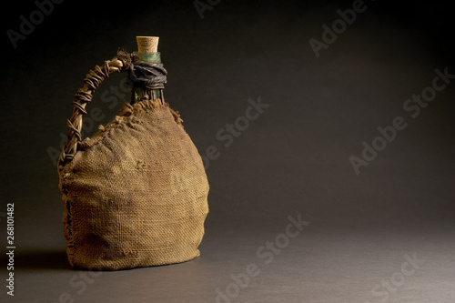 Old bottle with wicker basket. Isolated on dark background. With space copy text. Studio Shot.