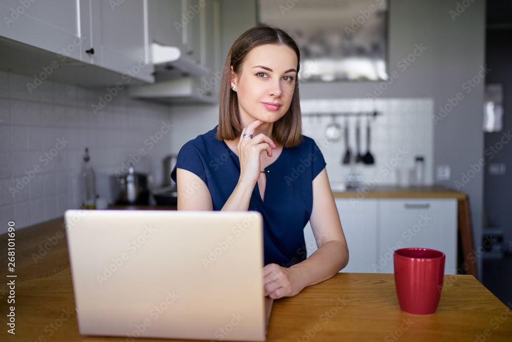 Freelance concept. Cozy home. Pretty young woman working on laptop computer while sitting at kitchen. Freelance concept. Cozy home. Pretty young woman working on laptop computer while sitting at kitchen.