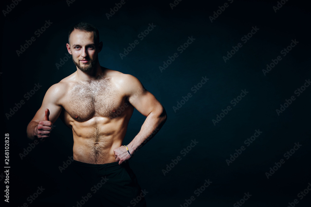 Fototapeta premium Low key portrait of muscular shirtless man gesturing thumb up