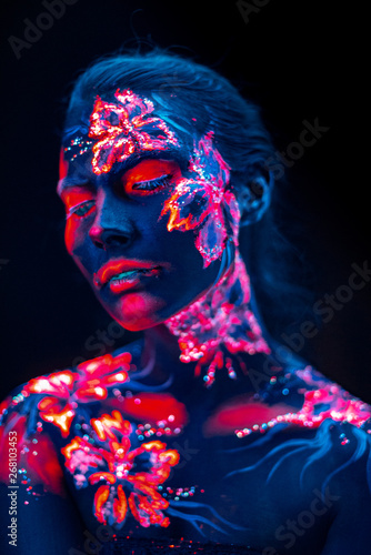 Beautiful flowers in UV light on a young girl face and body © multipedia