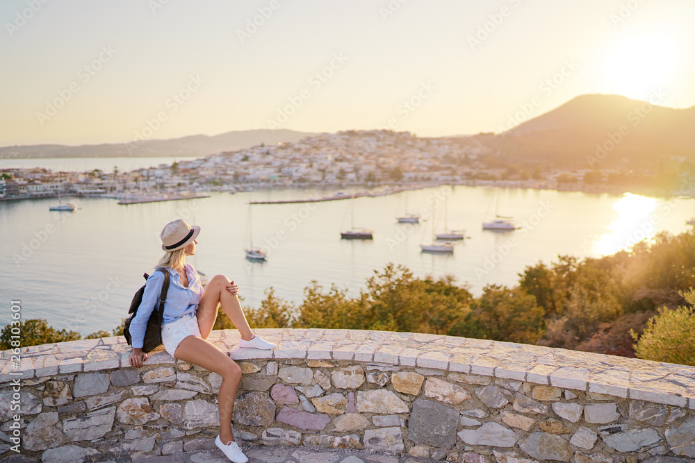 Enjoying vacation in Greece. Young traveling woman enjoying sunset on sea view point.