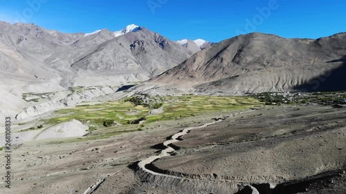 4k aerial fly through dry mountain valley with green settlement in Ladakh in India