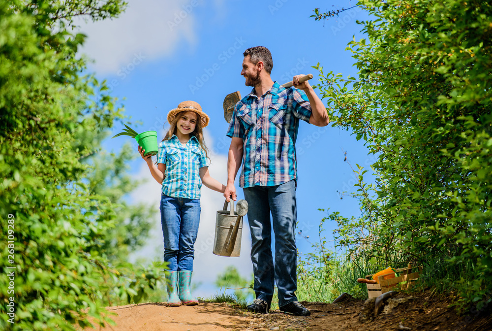 Making the world green. shovel and watering can. kid worker with dad hold box. family bonding. spring country side village. father and daughter on rancho. summer farming. farmer man with little girl Making the world green. shovel and watering can. kid worker with dad hold box. family bonding. spring country side village. father and daughter on rancho. summer farming. farmer man with little girl