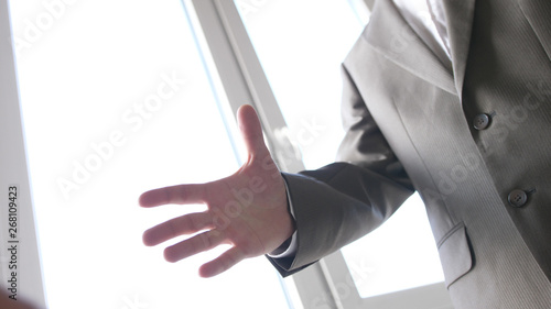 Businessman holds hand in suit before shaking hands.