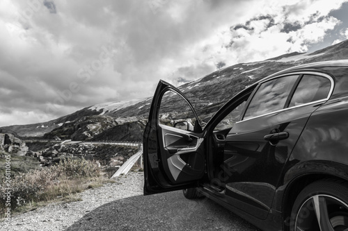 Black car with an open driver door, on a mountain road, in Norway