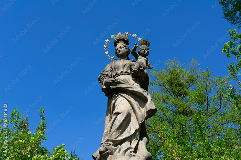 Historical religious statue of Virgin Mary with Jesus ( Madonna ) - christian monument and landmark is made of stone. 