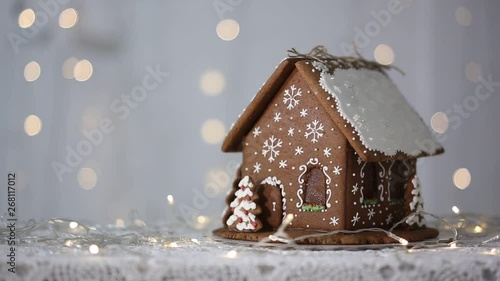 Handmade gingerbread house on the background of sparkling lights, decorated with snowflakes