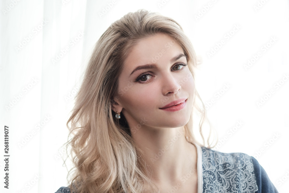 Beautiful young woman blonde in a blue robe by the window. Beautiful young woman blonde in a blue robe by the window.