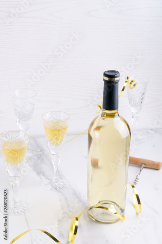 Concept of celebration party.Bottle of wine  full and empty glasses  holiday decoration on the white table against bright background