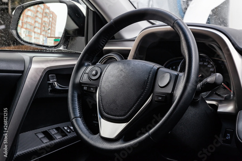 View to the black color interior of suv car with front seats, steering wheel and dashboard  with gray leather upholstery after cleaning and detailing in vehicle repair workshop. Auto service industry. © Aleksandr Kondratov