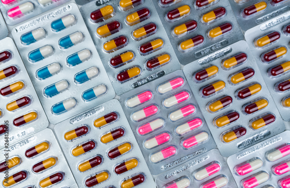 Top view of colorful antibiotic capsule pills in blister pack. Antibiotic drug resistance. Pharmaceutical industry. Pharmacy drug store background. Global health care. Antimicrobial capsule pills. Top view of colorful antibiotic capsule pills in blister pack. Antibiotic drug resistance. Pharmaceutical industry. Pharmacy drug store background. Global health care. Antimicrobial capsule pills.