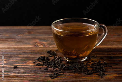 Cup of black tea on dark wooden background.
