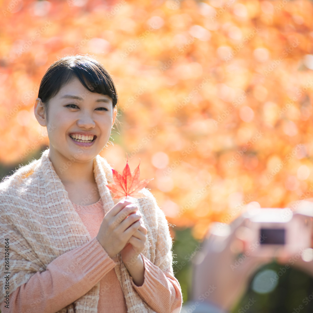 Obraz premium 紅葉を持ち微笑む女性