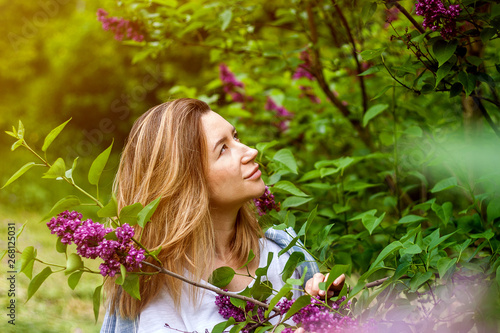 Woman in blossoming lilac bush in the sunny summer day