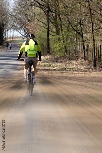 Cyclist rides along the park alley, artistically blurred image, speed lines