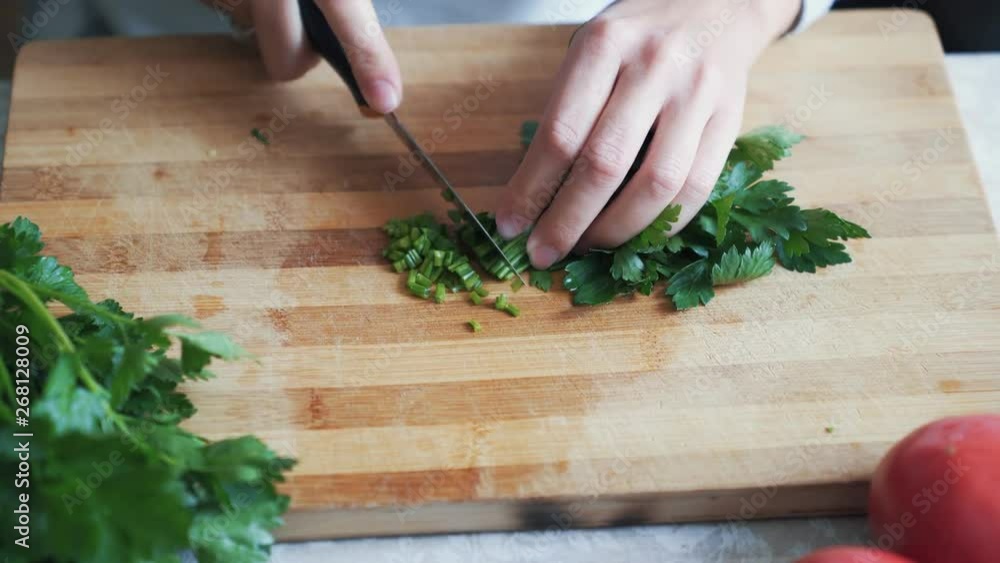Close up woman hands with knife cutting parsley on wooden board. Concept greens Close up woman hands with knife cutting parsley on wooden board. Concept greens